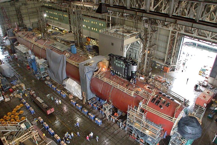 A submarine hull under construction in a shipyard hall