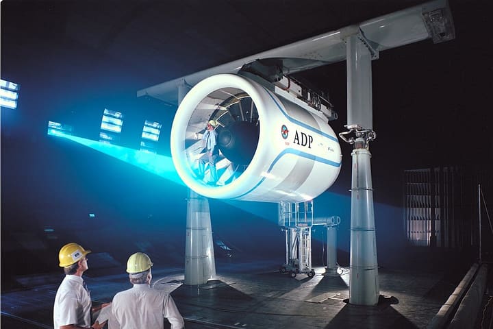 Engineers in hard hats watching a large engine on a test stand
